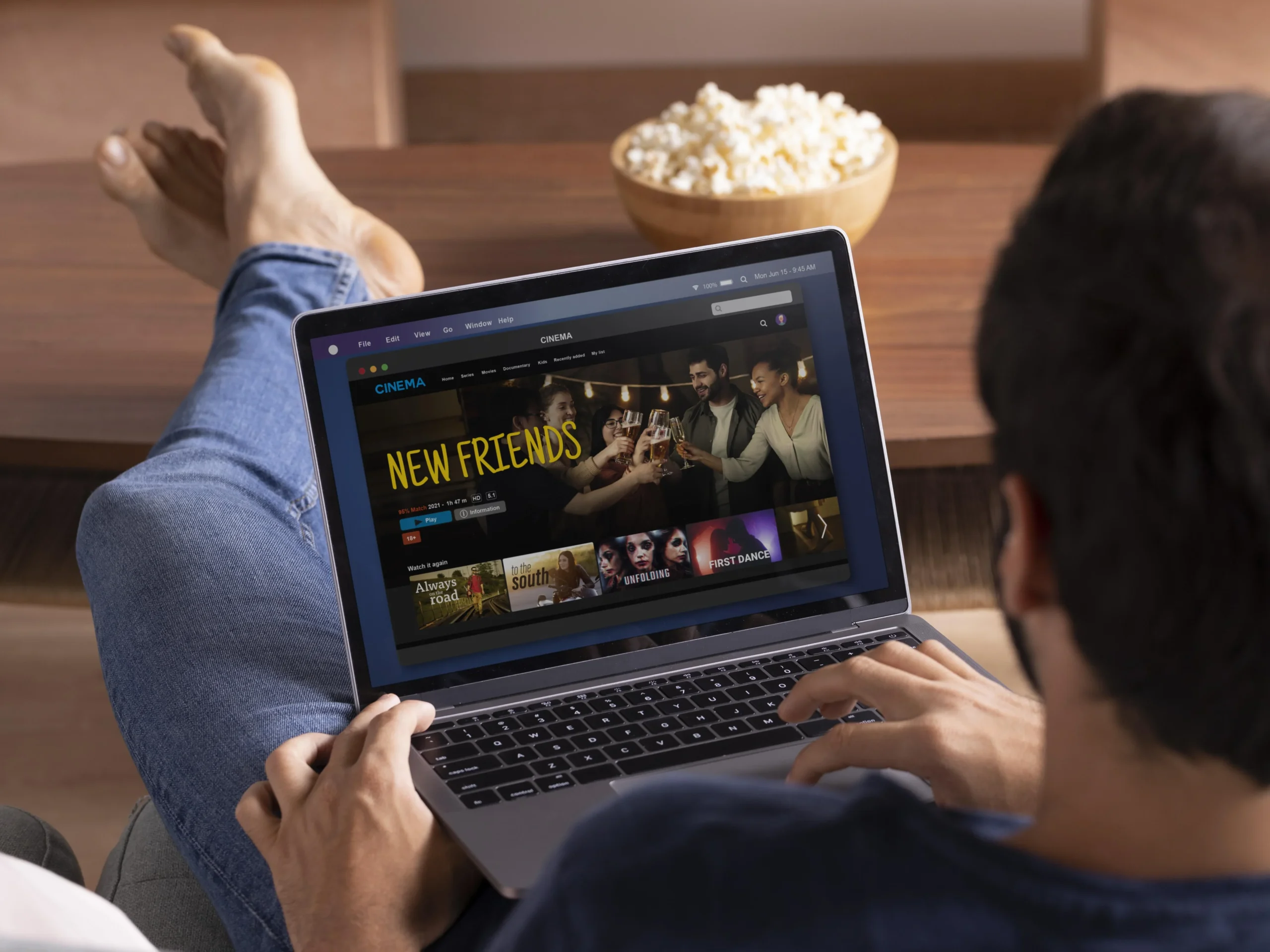 Person relaxing with a laptop browsing a movie streaming site, a bowl of popcorn beside them